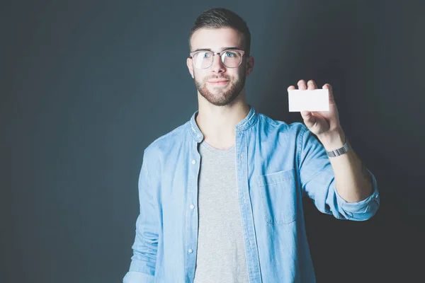 Young man holding a credit card standing on gray background. Young entrepreneur. — Stock Photo, Image