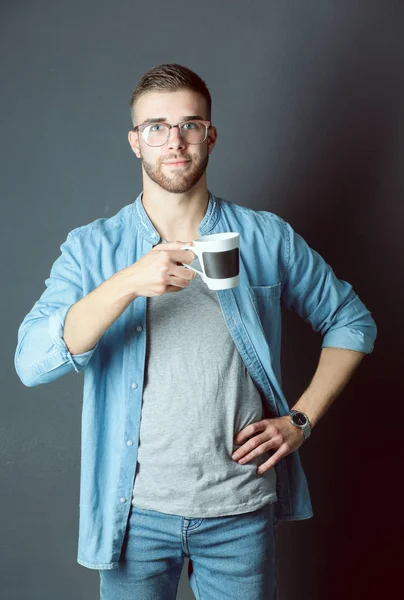 Ritratto di un bel giovanotto in piedi con in mano una tazza di caffè — Foto Stock