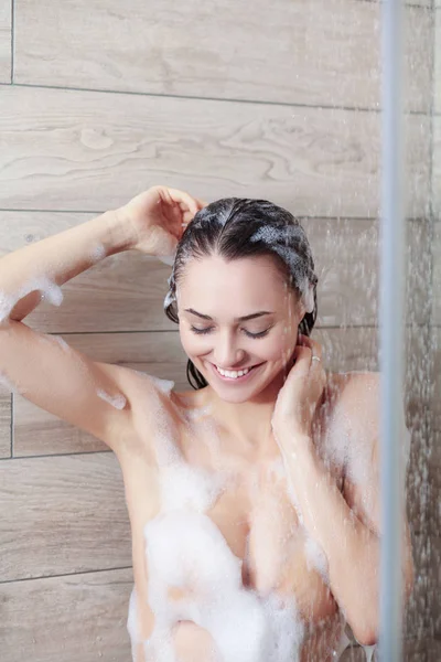 Jeune femme belle sous la douche dans la salle de bain . — Photo