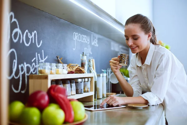 Porträtt av ung kvinna som står mot kök bakgrund. — Stockfoto