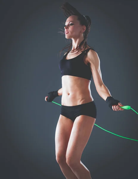 Muscular young woman standing on gray background. Muscular young woman. beautiful girl jumping rope — Stock Photo, Image