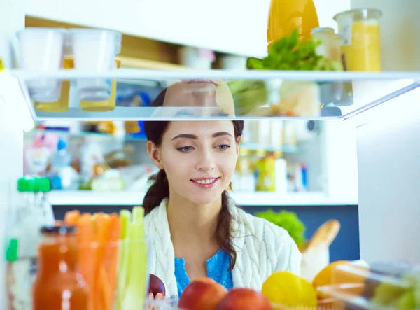 Portrait of female standing near open fridge full of healthy food, vegetables and fruits. Portrait of female — Stock Photo, Image