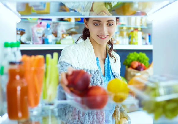 Portrait of female standing near open fridge full of healthy food, vegetables and fruits. Portrait of female — Stock Photo, Image