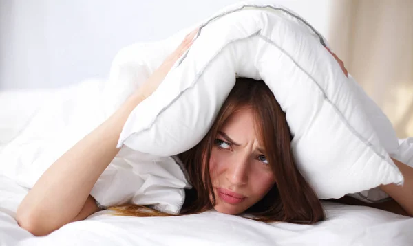 Mujer acostada en la cama y cerrando las orejas con almohada — Foto de Stock