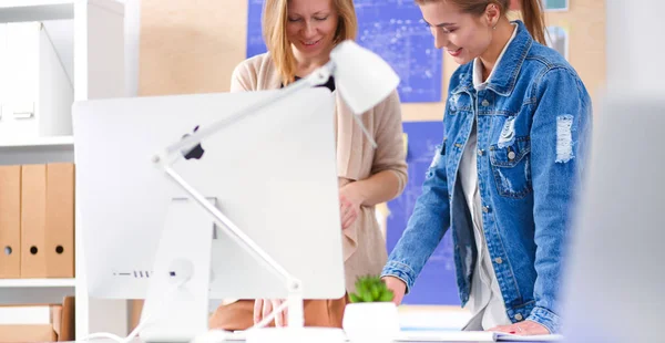 Két fiatal nő áll az íróasztal mellett műszerekkel, tervvel és laptoppal. — Stock Fotó