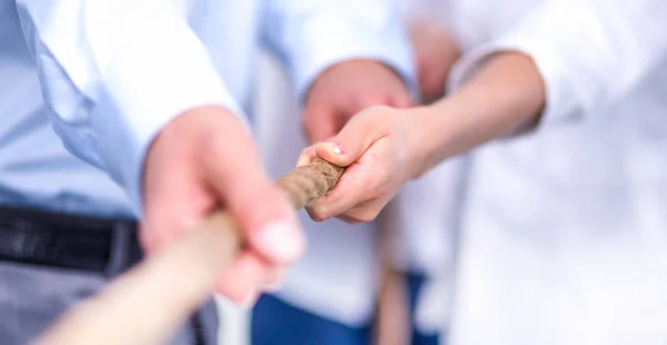 Konzeptbild eines Geschäftsteams, das ein Seil als Element der Teamarbeit im Vordergrund verwendet — Stockfoto