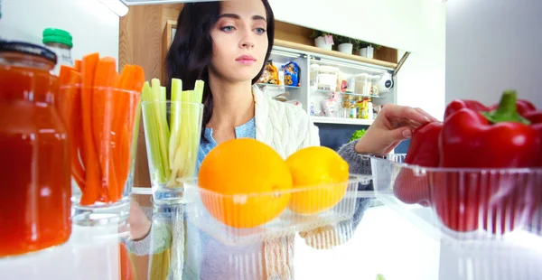 Portrét ženy stojící u otevřené ledničky plné zdravého jídla, zeleniny a ovoce. Portrét ženy — Stock fotografie