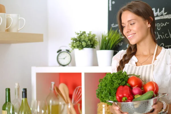 Usmívající se mladá žena držící zeleninu v kuchyni. Usmívající se mladá žena — Stock fotografie