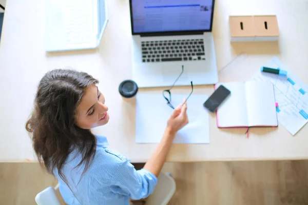 Mladá žena sedí v kanceláři a dívá se na monitor notebooku. Mladá žena — Stock fotografie