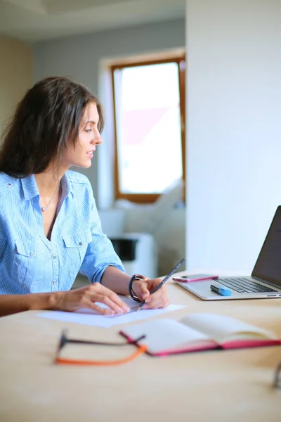 Ofis masasında dizüstü bilgisayarla oturan genç bir kadın. Genç bir kadın. Dizüstü bilgisayar — Stok fotoğraf