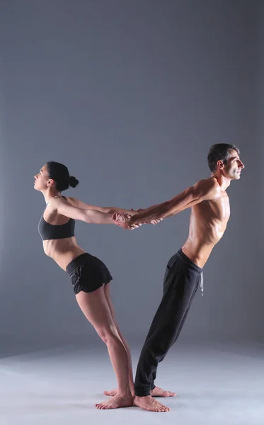 Pareja joven practicando acro yoga en estera en estudio juntos. Acroyoga. Un par de yoga. Socio yoga . —  Fotos de Stock