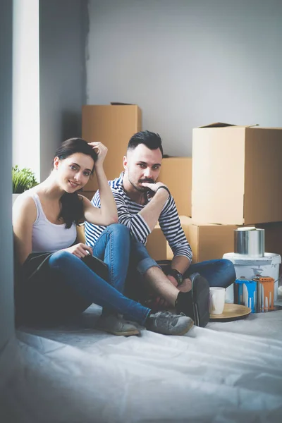 Couple moving in house sitting on the floor . Couple
