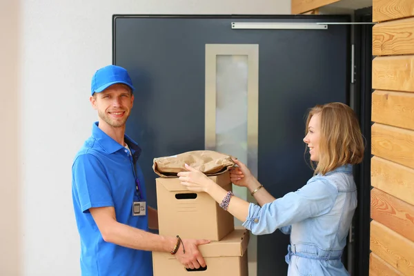 Leende leverans man i blå uniform leverera paket låda till mottagaren - kurir service koncept. Leende leverans man i blå uniform — Stockfoto