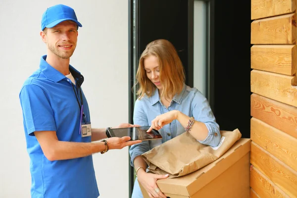 Leende leverans man i blå uniform leverera paket låda till mottagaren - kurir service koncept. Leende leverans man i blå uniform — Stockfoto