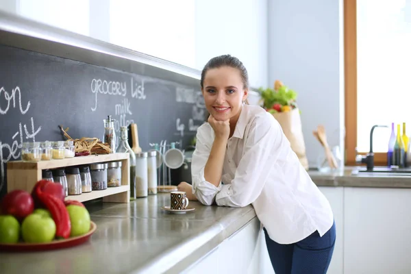 Retrato de mujer joven de pie sobre el fondo de la cocina . —  Fotos de Stock