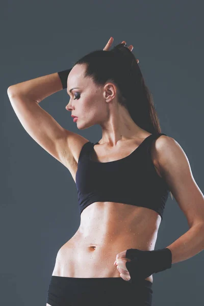 Muscolosa giovane donna in piedi su sfondo grigio. Muscolare giovane donna — Foto Stock