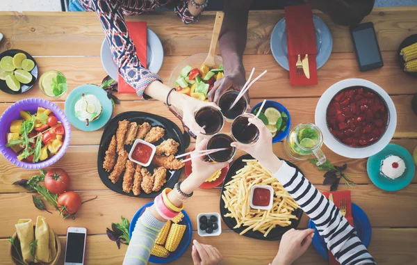 Top view of group of people having dinner together while sitting at wooden table. Food on the table. People eat fast food. — Stock Photo, Image