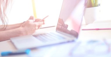 Dizüstü bilgisayar ekranına bakarak office tablosunda oturan genç kadın