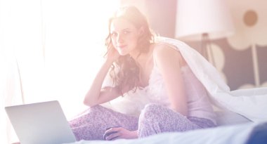 Evde dizüstü bilgisayar kullanan genç bir kadın.