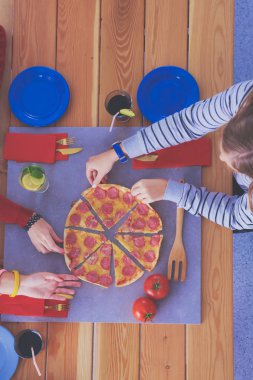 Ahşap masada otururken birlikte yemek yiyen bir grup insanın üst düzey görüntüsü. Masada yemek var. İnsanlar fast food yiyor..