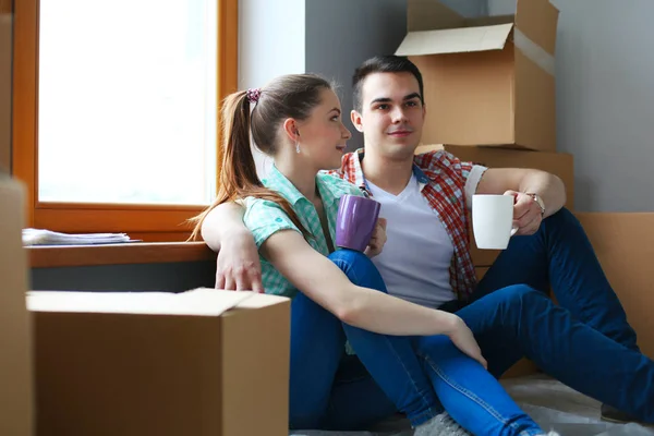 Couple moving in house sitting on the floor. Couple