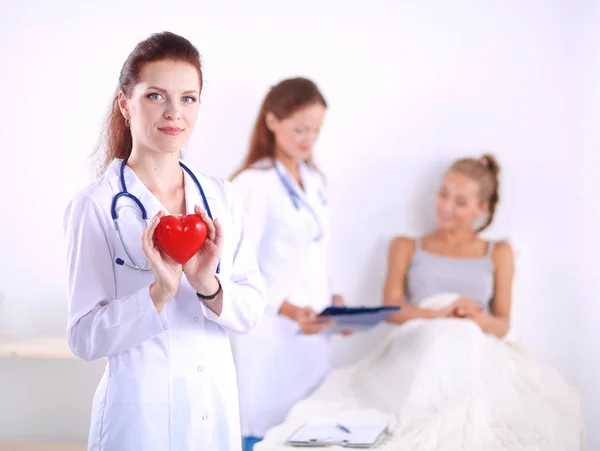 Vrouw arts withred hart symbool staande in ziekenhuis. Vrouw arts — Stockfoto