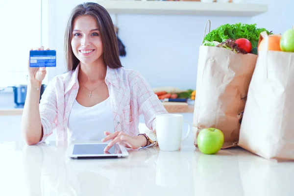 Een jonge vrouw in de keuken, die haar ipad gebruikt. Jonge vrouw — Stockfoto