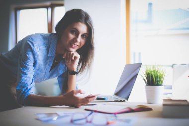 Ofis masasında oturan ve cep telefonuyla konuşan genç ve güzel bir iş kadını. İş kadını