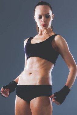 Gri arka plan üzerinde duran kas genç kadın. Kas genç kadın