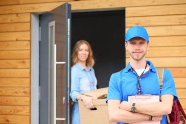 Mavi üniformalı gülümseyen kurye servis konseptine paket kutusu teslim eden teslimatçı. Mavi üniformalı gülümseyen teslimatçı.