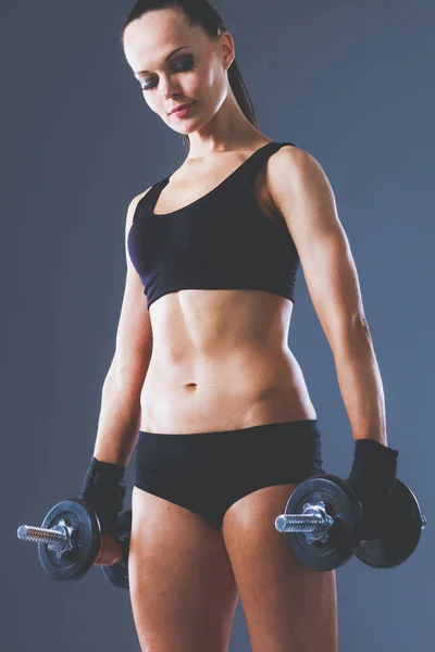 Muskulös ung kvinna stående på grå bakgrund. Muskulös ung kvinna — Stockfoto