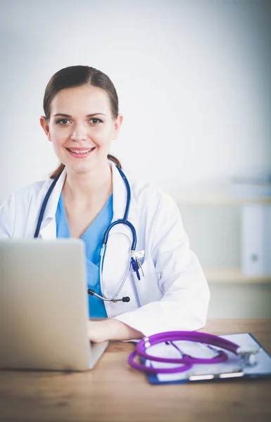 Vakker, ung, smilende kvinnelig lege som sitter ved skrivebordet og skriver. kvinnelig lege – stockfoto