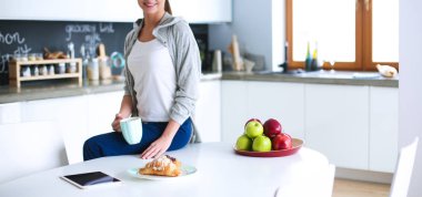 Mutfakta dijital tablet kullanan genç kadın. Kahve içme ve dijital tablet sabah kullanma kadın.