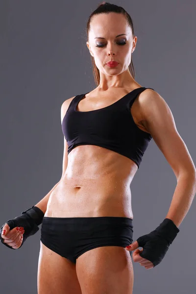 Mujer joven musculosa de pie sobre fondo gris. Mujer joven musculosa — Foto de Stock