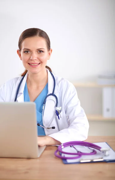 Krásná mladá usmívající se lékařka sedí u stolu a psaní. ženský lékař — Stock fotografie