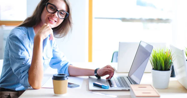 Giovane donna seduta al tavolo dell'ufficio, guardando lo schermo del computer portatile — Foto Stock