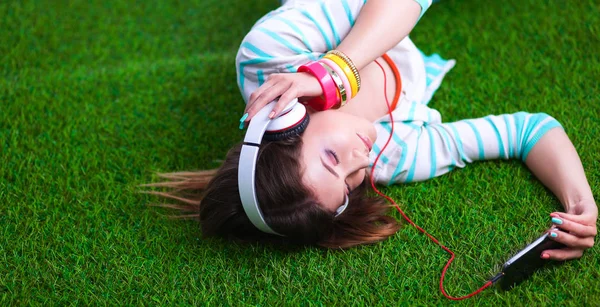 Vrouw luisteren naar de muziek liggen op gras — Stockfoto