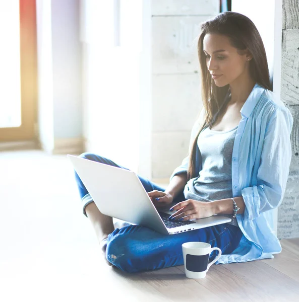 Unga vackra kvinnan hemma sitter på golvet med laptop — Stockfoto