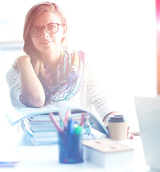 Jeune femme assise à un bureau parmi les livres — Photo