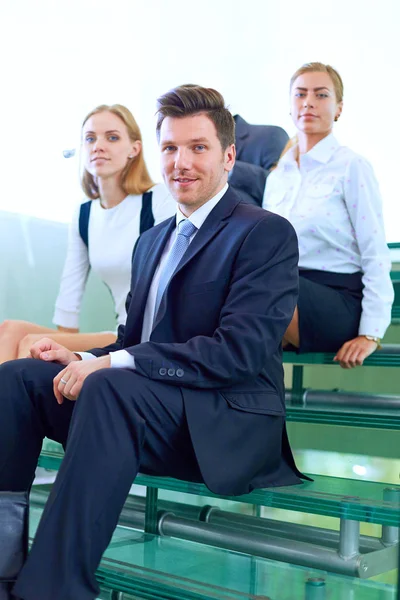 Porträt eines jungen Geschäftsmannes im Amt mit Kollegen im Hintergrund. Porträt eines jungen Geschäftsmannes. — Stockfoto