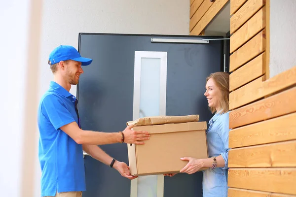 Leende leverans man i blå uniform leverera paket låda till mottagaren - kurir service koncept. Leende leverans man i blå uniform — Stockfoto