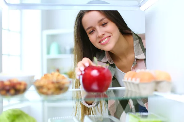 Portret van een vrouw in de buurt van een open koelkast vol gezond voedsel, groenten en fruit. Portret van een vrouw — Stockfoto