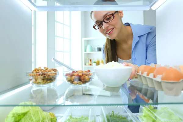 Портрет женщины, стоящей рядом с открытым холодильником, полным здоровой пищи, овощей и фруктов. Портрет женщины — стоковое фото