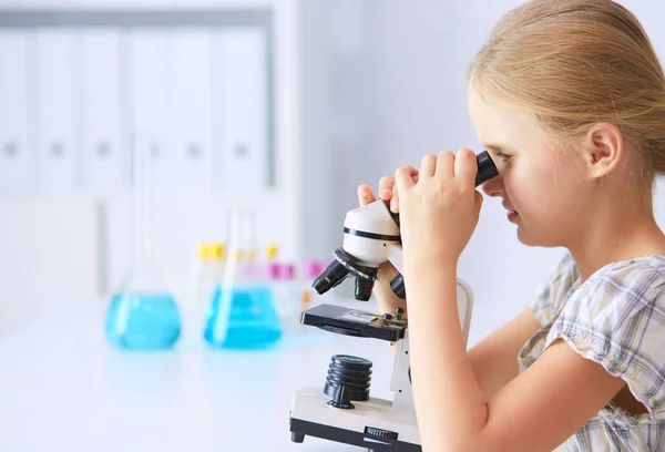 Colegiala mirando a través del microscopio en la clase de ciencias . — Foto de Stock