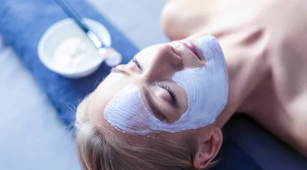 Маска для лица. Красивая молодая девушка в спа, косметолог надевает маску для лица — стоковое фото