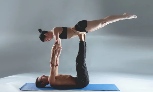 Pasangan muda berlatih akroyoga di atas tikar di studio bersama-sama. Acroyoga. Beberapa yoga. Partner yoga . — Stok Foto