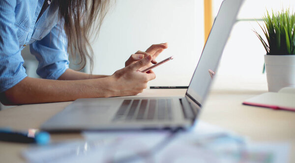 Beautiful young business woman sitting at office desk and talking on cell phone. Business woman