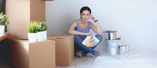 Mujer eligiendo el color de la pintura de la muestra para el nuevo hogar sentado en el suelo de madera. Mujer en la casa — Foto de Stock