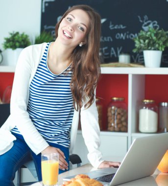 Mutfakta dijital tablet kullanan genç kadın. Kahve içme ve dijital tablet sabah kullanma kadın.