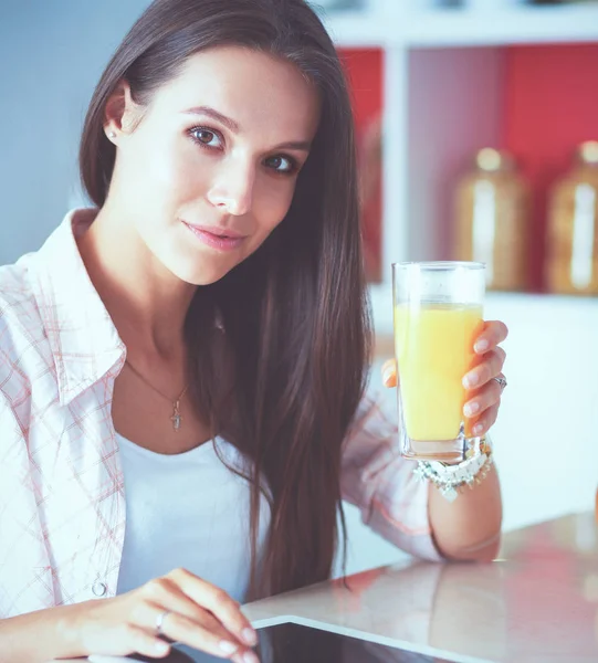 Młoda kobieta za pomocą cyfrowego tabletu w kuchni. Kobieta pije kawę i za pomocą cyfrowego tabletka rano. — Zdjęcie stockowe